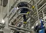 Technician climbing caged ladder among industrial pipes in commercial facility